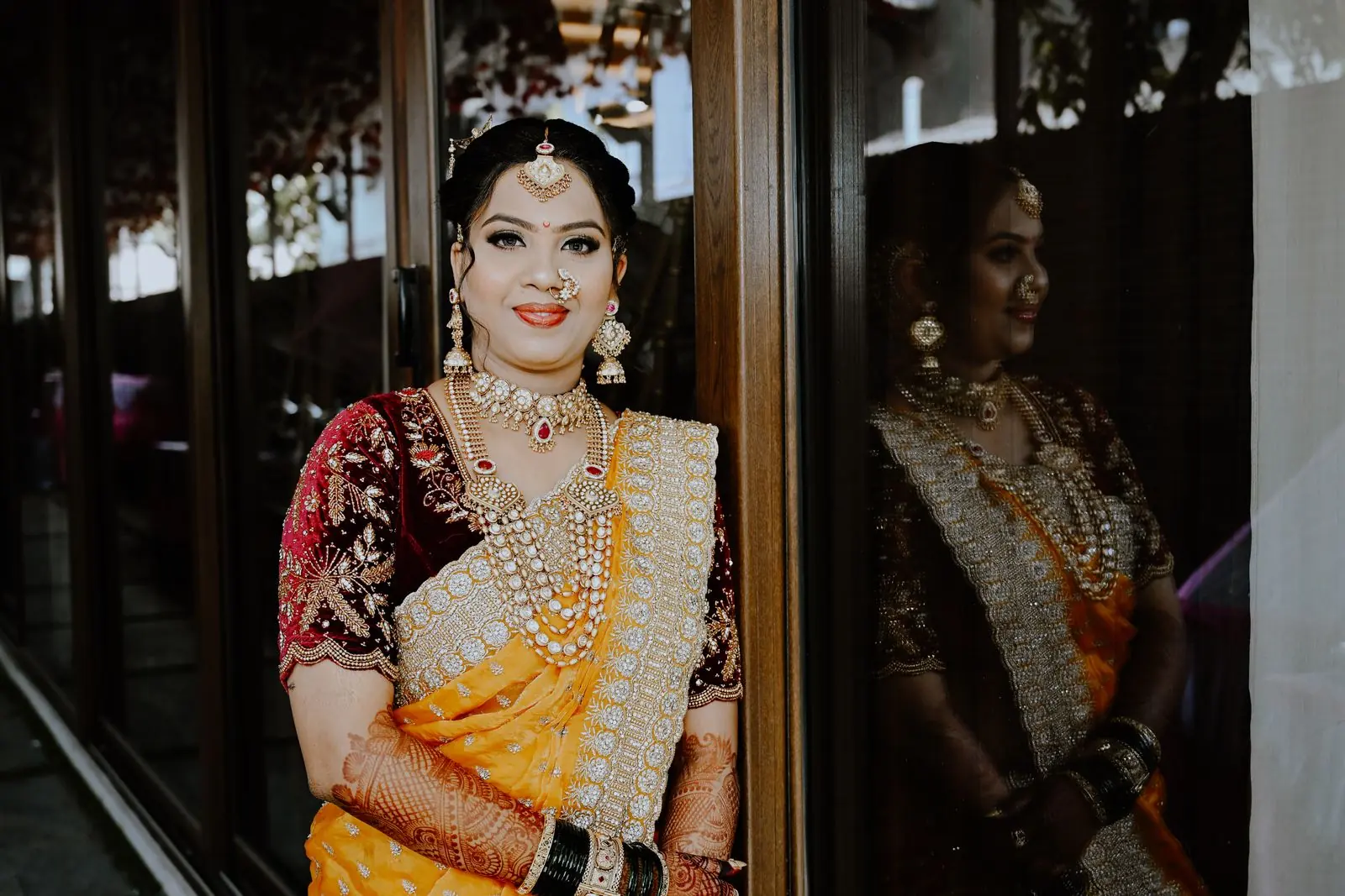 A bride in a golden-yellow silk saree and heirloom jewellery